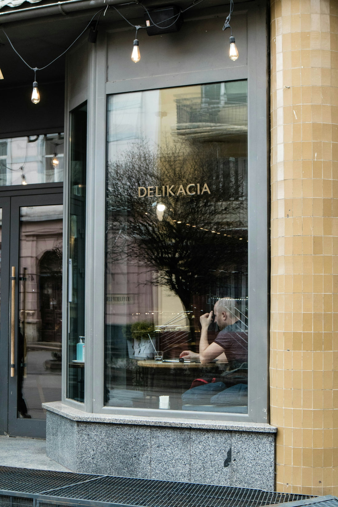 a man sitting outside of a restaurant talking on a cell phone